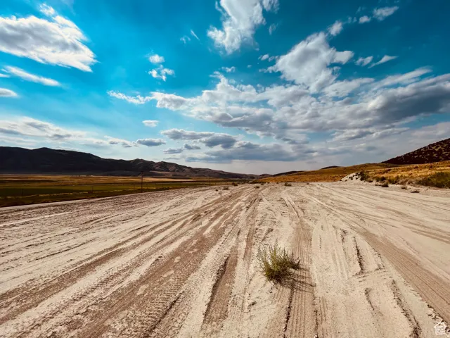 Expansive land parcel featuring a wide, unpaved road and distant mountains