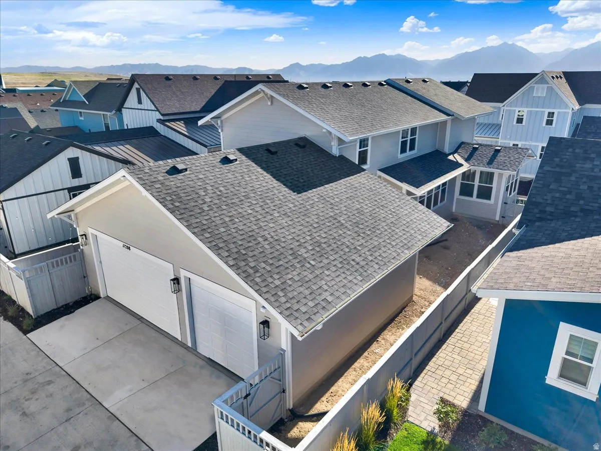 Two-car garage with modern lighting fixtures, asphalt shingle roofing, and a concrete driveway