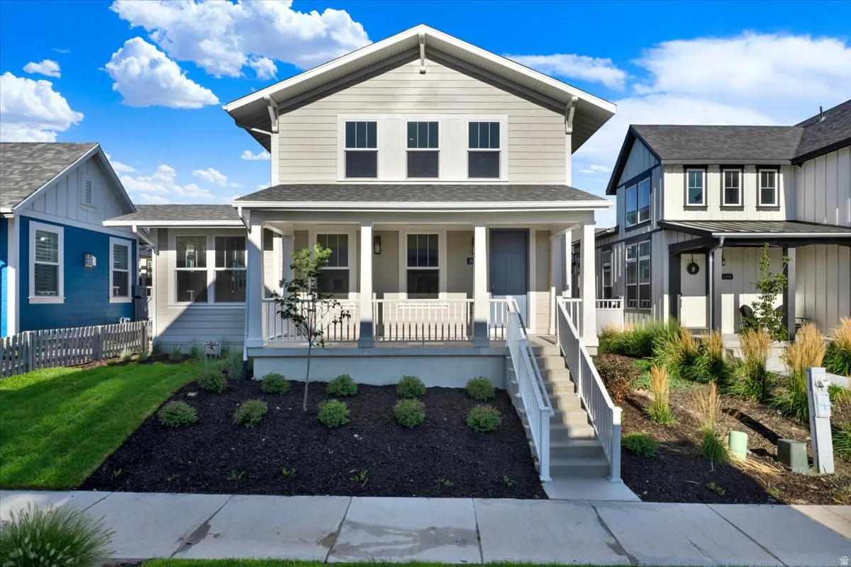 Two-story residence featuring light gray siding with white trim, a covered front porch, and a dark gray shingle roof