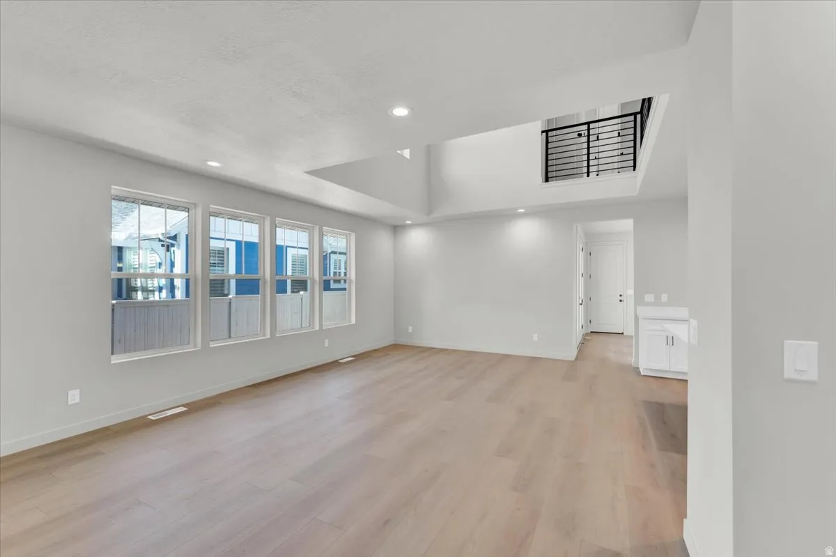 Expansive living area with wood-finish flooring, recessed lighting, and a two-story ceiling