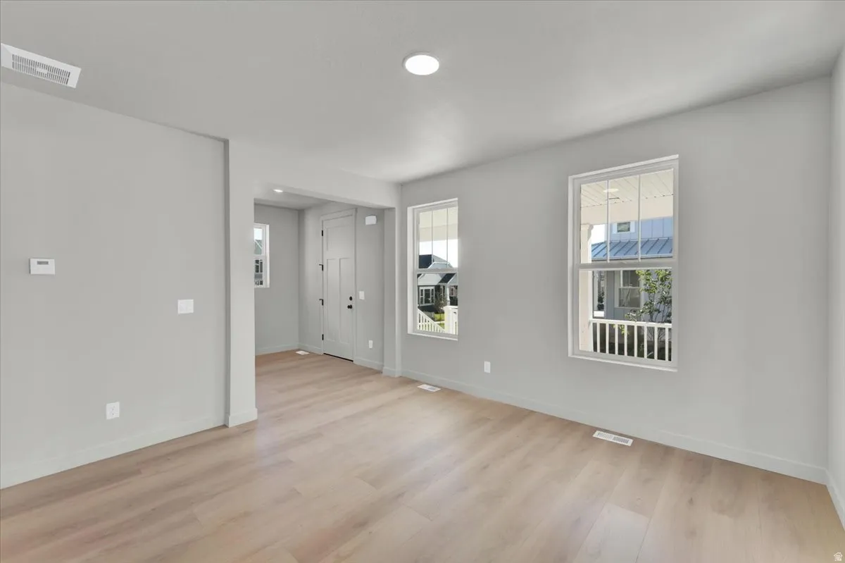 Light-toned wood-finish flooring, recessed ceiling lighting, and two windows with white frames