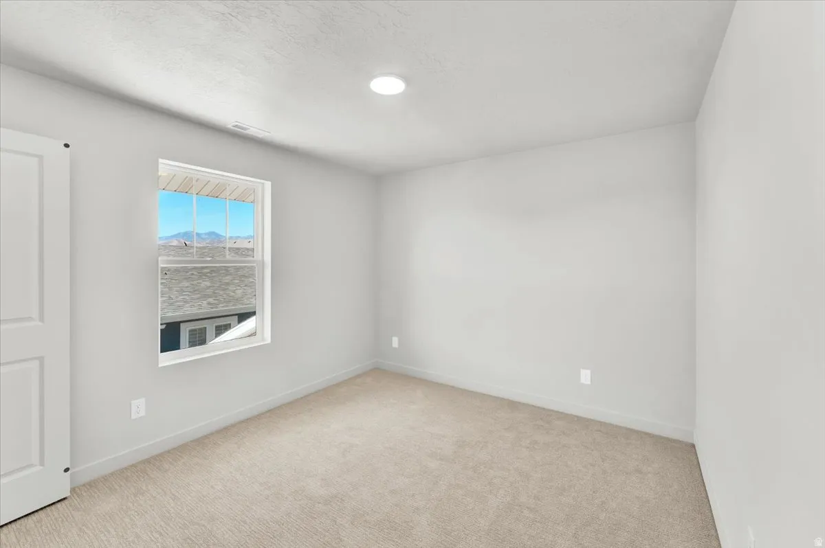 Neutral painted walls, plush carpeting, recessed ceiling lighting, and a white-framed window