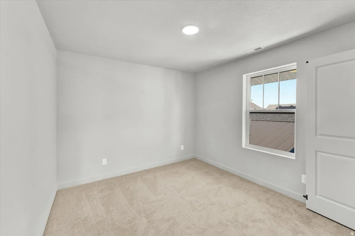 Recessed lighting, light gray wall finish, neutral tone carpet, white trim, and a window with white casing