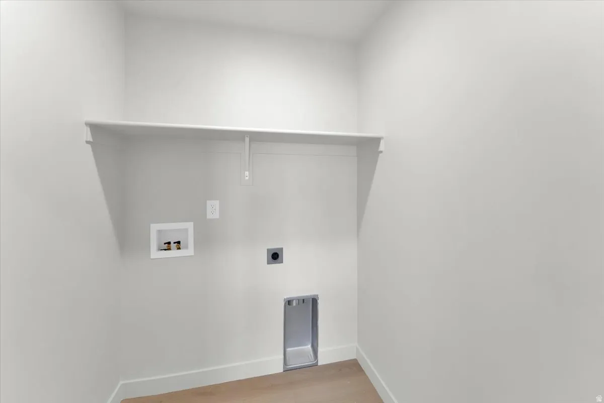 White shelving unit, wall-mounted electrical outlet, and plumbing hookups