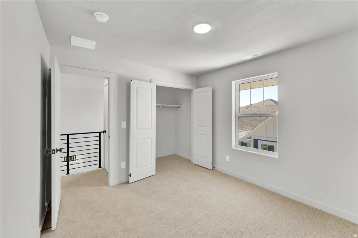 Recessed ceiling lighting, neutral-toned wall paint, white trim, carpet flooring, and a window with white casing