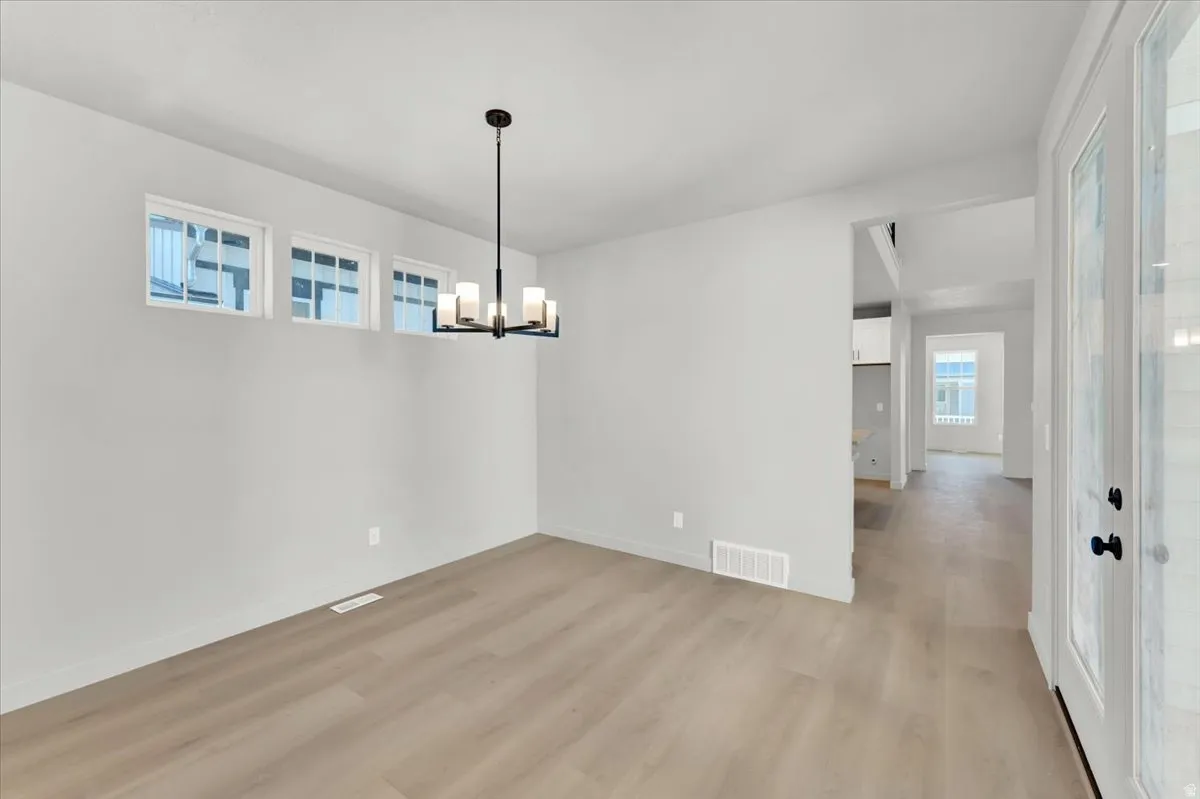 Light wood-finish flooring throughout, complemented by a contemporary chandelier and multiple transom windows