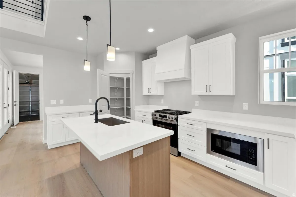 Kitchen featuring a center island, white cabinetry, integrated stainless steel appliances, and wood-finish flooring