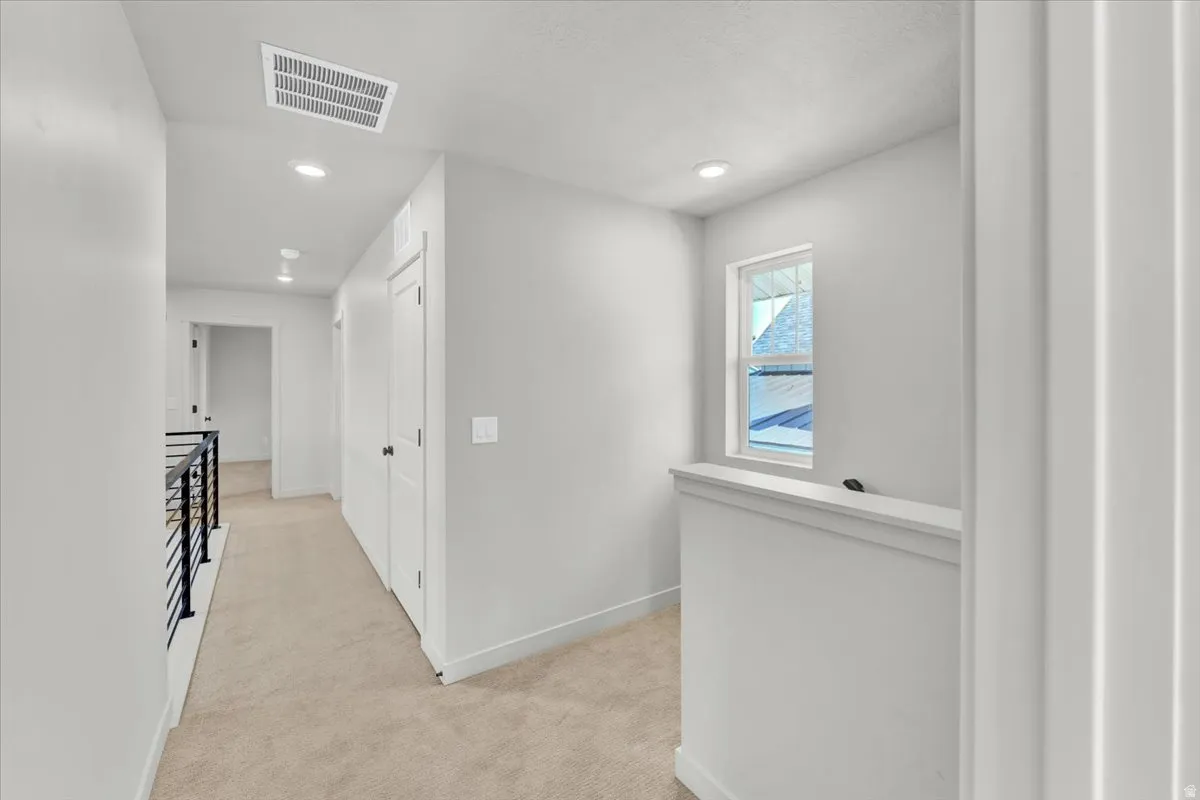 Plush carpeting, recessed lighting, white walls, and a modern black metal railing