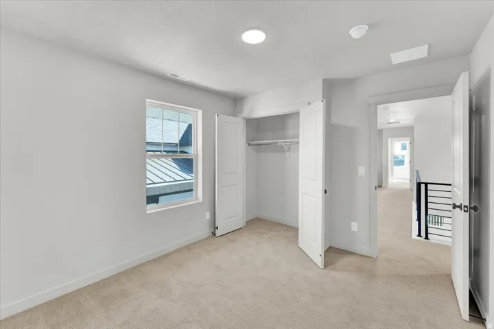 Wall-to-wall carpeting, double-door closet, recessed lighting, and a single window with a white frame