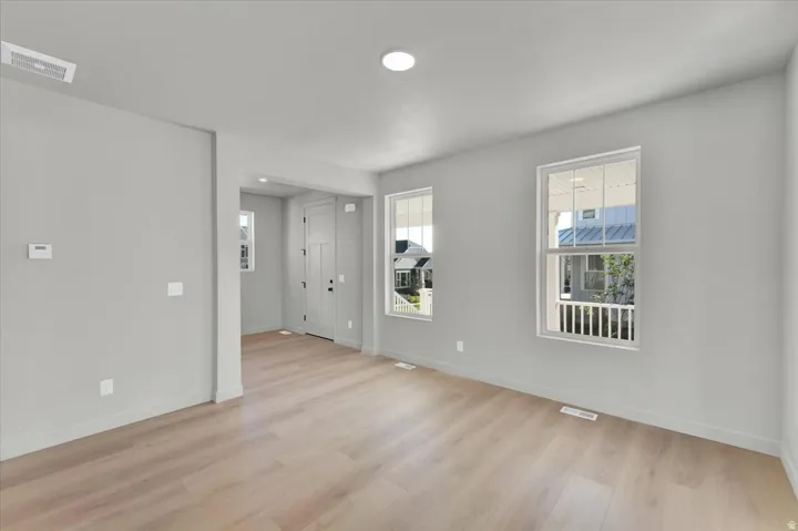 Light-toned wood-finish flooring, recessed ceiling lighting, and two windows with white frames