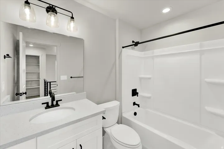 White vanity with shaker-style cabinetry, a built-in sink, and a light-toned countertop