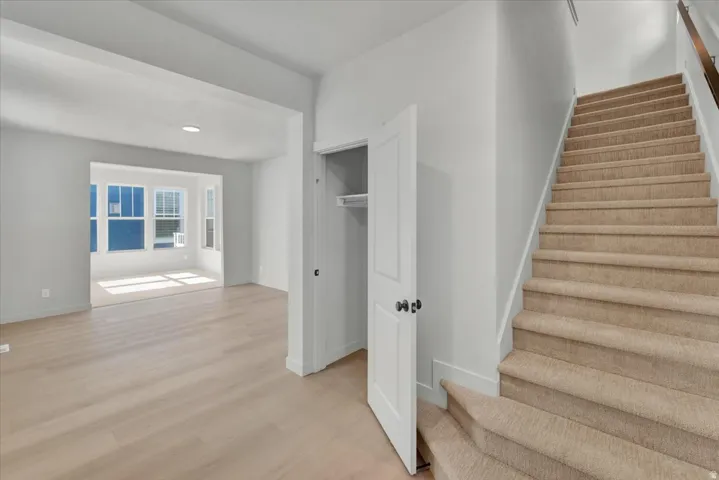 Light wood-finish flooring, recessed lighting, carpeted staircase, paneled interior door, and a multi-pane bay window