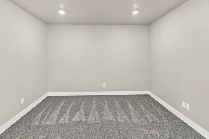 Recessed ceiling lighting illuminates neutral wall finishes and gray patterned carpeting