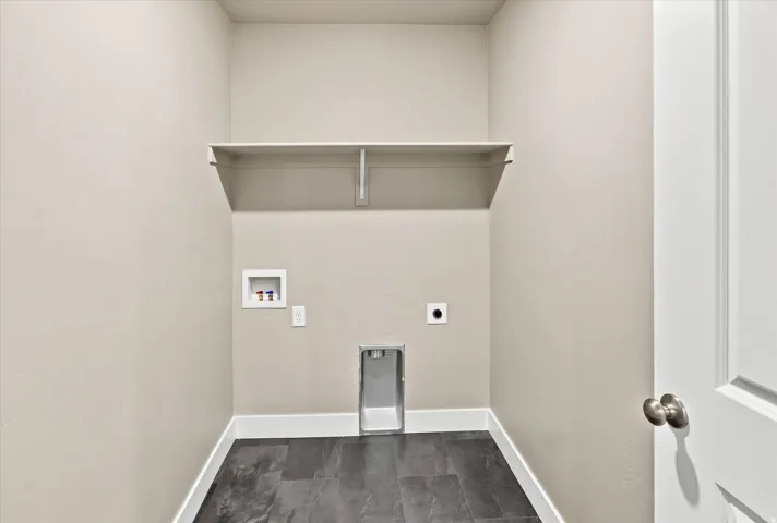 Utility space featuring a built-in shelf, dark tile flooring, and white trim