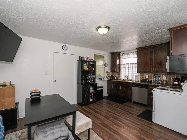 Well-appointed kitchen featuring wood-finish flooring, dark wood cabinetry, and a tile backsplash