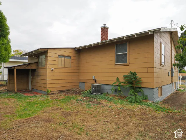 Exterior profile featuring horizontal siding, a red brick chimney, and an attached covered storage area