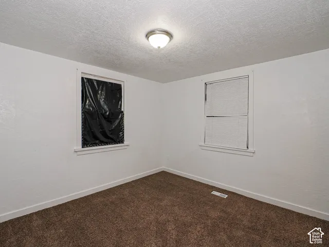 Neutral-toned interior space featuring textured walls, wall-to-wall carpeting, and a flush-mount ceiling fixture