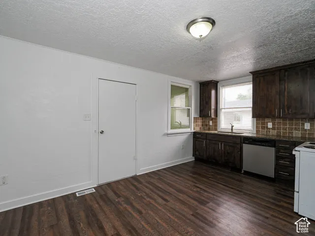Kitchen featuring dark wood cabinetry, stainless steel dishwasher, tile backsplash, wood-finish flooring, and recessed ceiling lighting