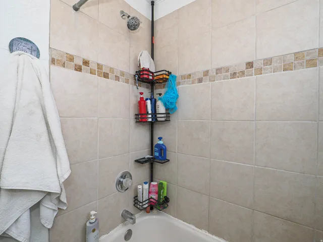 Tiled shower surround with a decorative accent band and a mounted showerhead