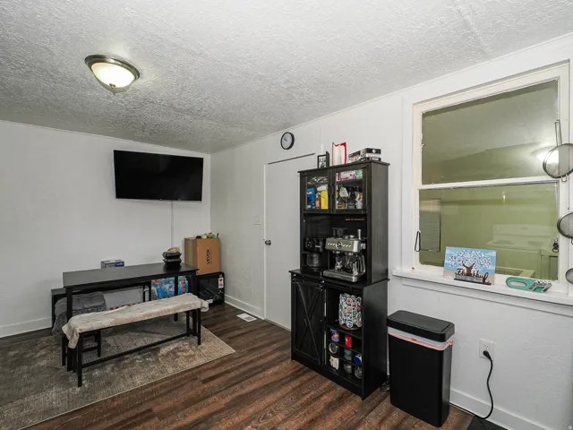 Wood-finish flooring with white wall paneling, a flush-mount ceiling light, and a white framed window