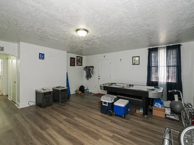 Wood-finish flooring throughout, white painted walls, and a ceiling-mounted light fixture