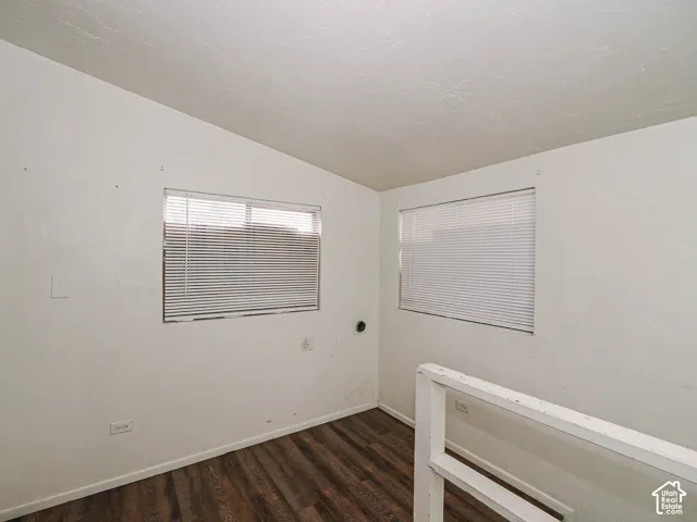 Wood-finish flooring, white walls, dual windows with integrated blinds, and a white architectural railing