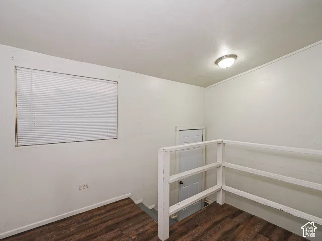 Wood-finish flooring, horizontal slat window blinds, and white painted wooden stair railing