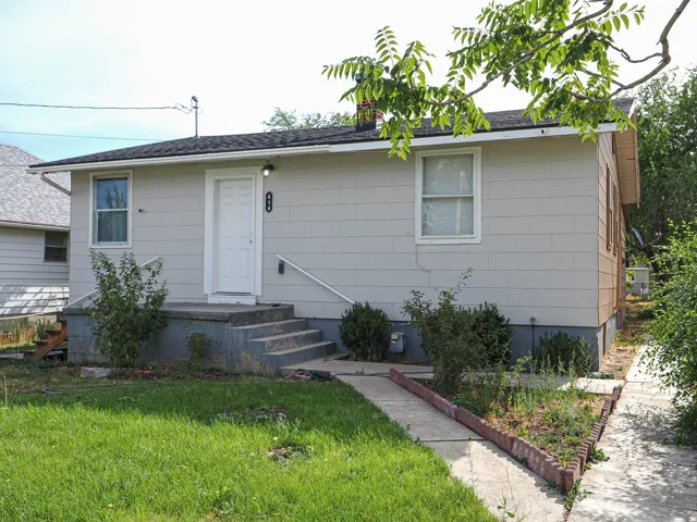 Single-story residence featuring light-colored siding, a white front door, and a concrete entry porch with steps