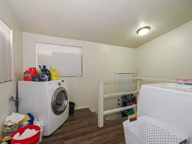 Laundry area featuring wood-finish flooring, two windows with blinds, and a flush mount ceiling light