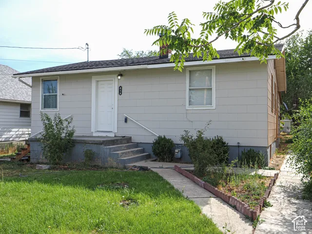 Single-story residence featuring light-colored siding, a white front door, and a concrete entry porch with steps