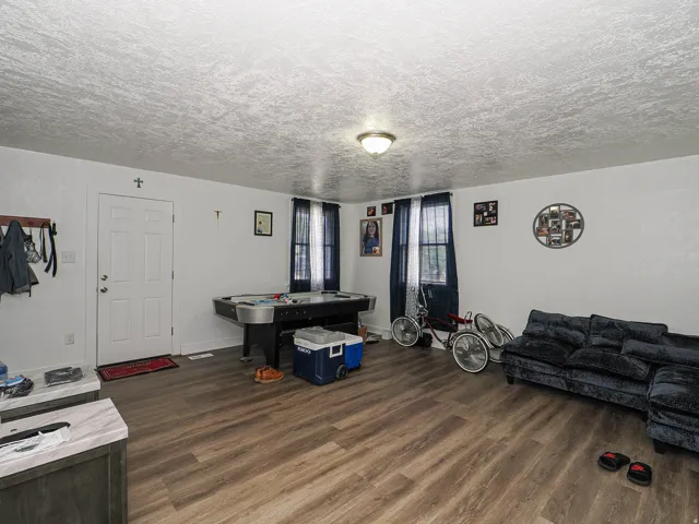 Wood-finish flooring, white painted walls, and two windows with dark curtains