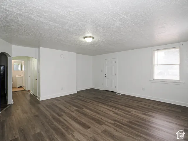 Interior space featuring wood-finish flooring, a neutral color palette, textured ceiling, and a six-panel door