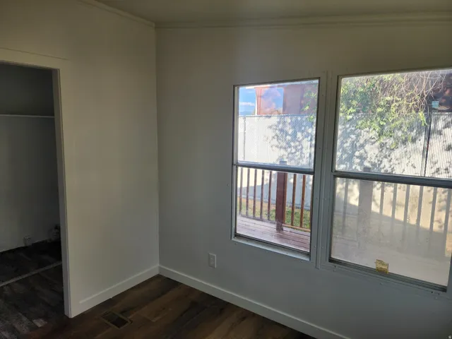 Wood-finish flooring, white trim, and two windows providing natural light
