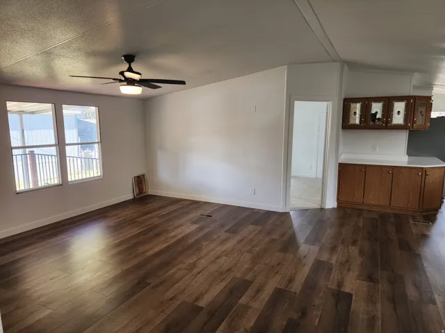 Wood-finish flooring throughout the main living area, featuring a ceiling fan with integrated lighting