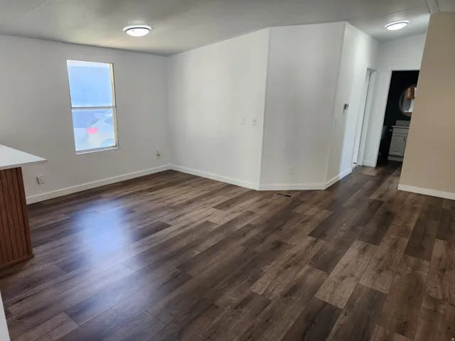 Wood-finish flooring, white walls, flush mount lighting, and a partial counter with white surface
