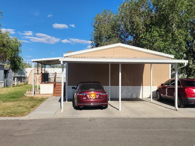 Carport with space for multiple vehicles, covered porch with railings, and a detached storage shed