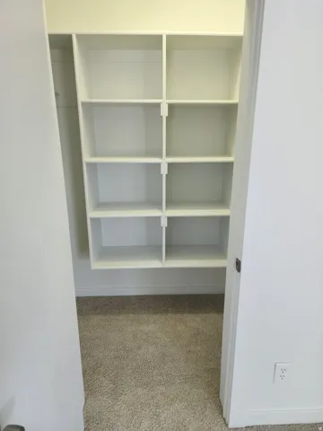 Built-in shelving with multiple compartments and neutral carpeting