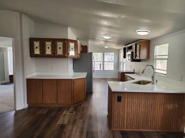 Wood-finish flooring, white countertops, stainless steel appliances, wood cabinetry, and recessed lighting