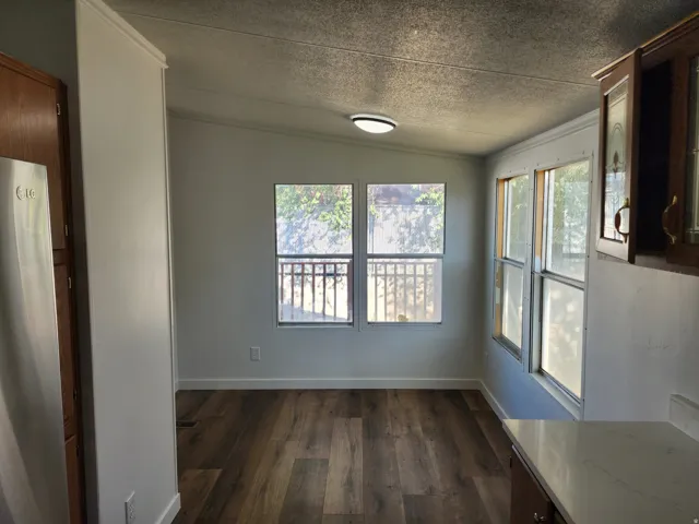 Wood-finish flooring, multiple windows, recessed lighting, white perimeter walls, and crown molding