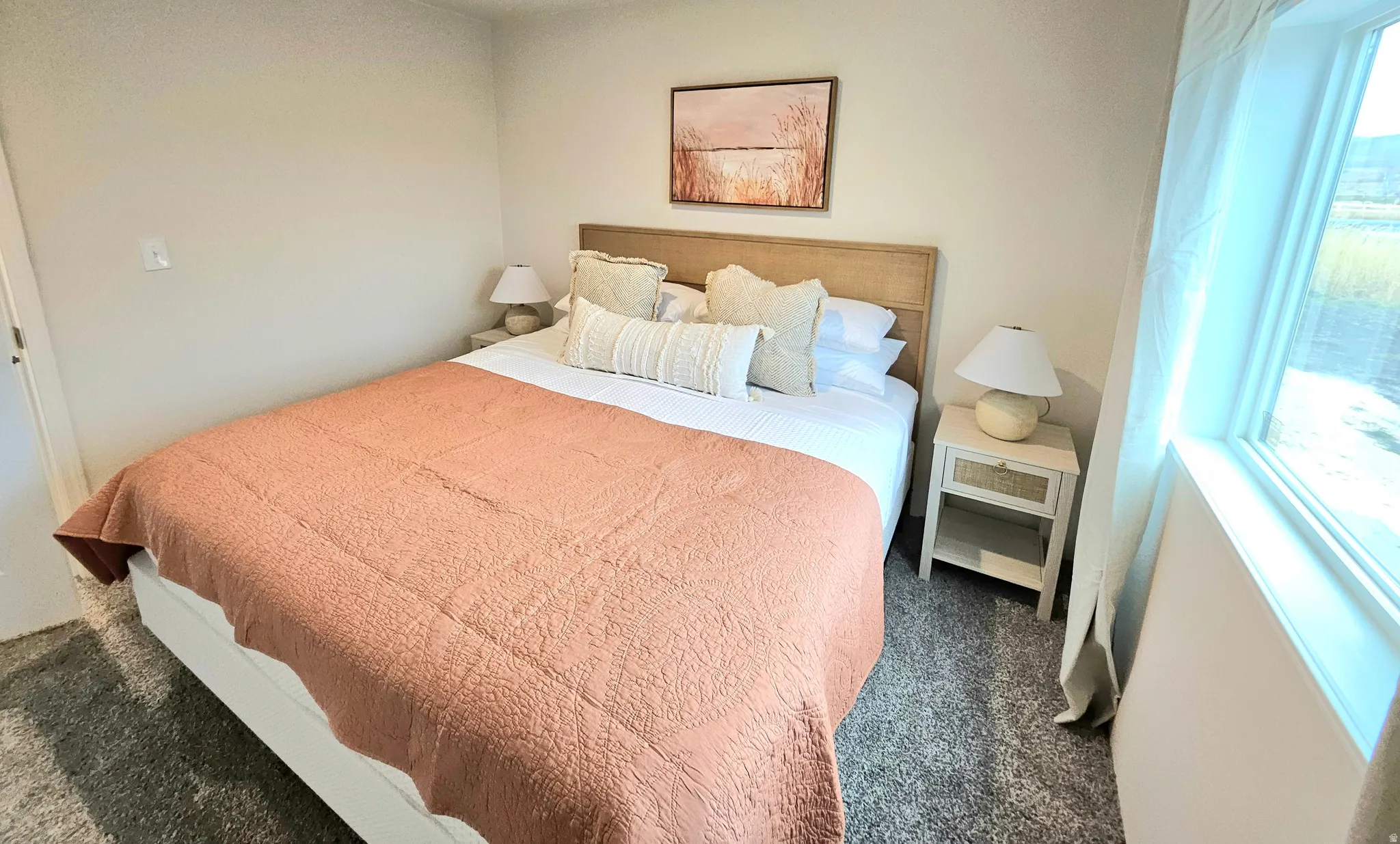 Carpeted flooring, window with natural light, neutral wall color, and a wood-finish headboard
