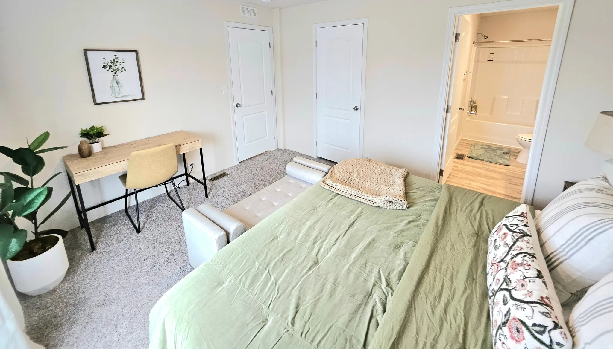 Carpeted bedroom featuring white paneled doors and a full bathroom with a white bathtub