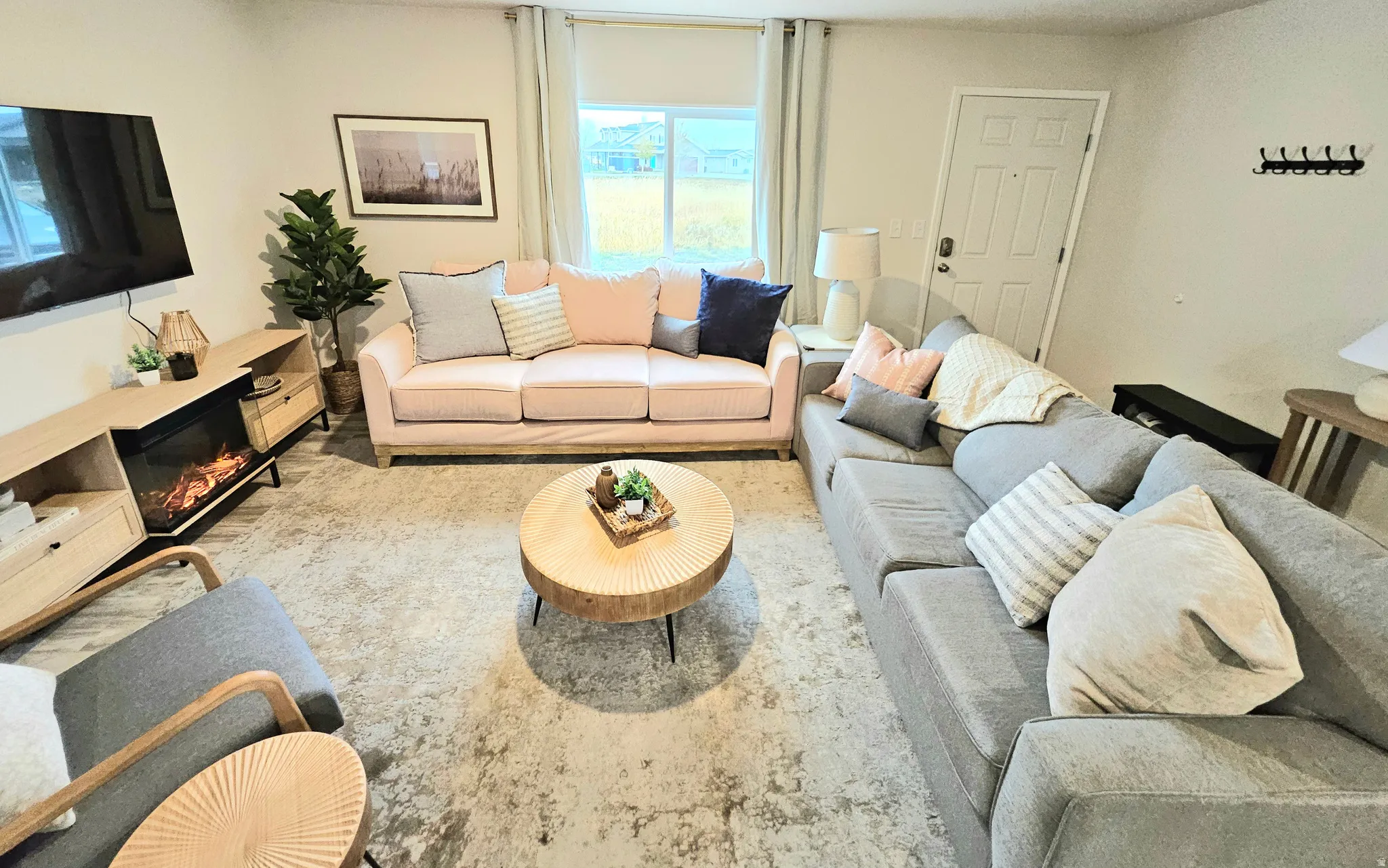 Living area with light wood-finish flooring, a built-in media console with a fireplace insert, and a white paneled entry door