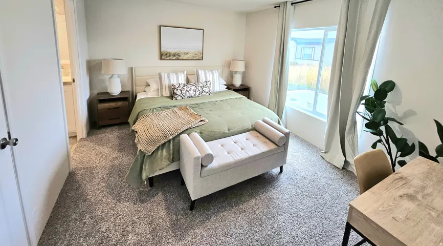 Carpeted room featuring a large window, a built-in closet with a white door, and a light-colored wooden headboard