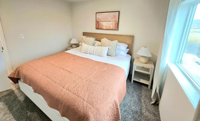 Carpeted flooring, window with natural light, neutral wall color, and a wood-finish headboard