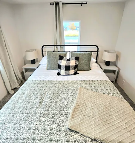 White walls with a window, black metal bed frame, and light gray nightstands