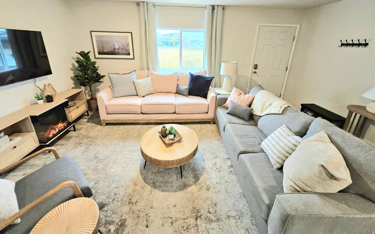 Living area with light wood-finish flooring, a built-in media console with a fireplace insert, and a white paneled entry door
