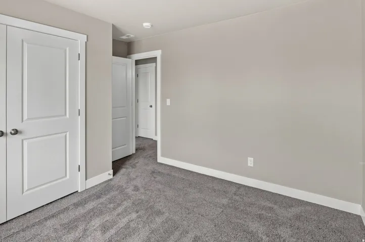 Gray wall-to-wall carpeting with white trim, featuring multiple paneled doors with spherical door hardware