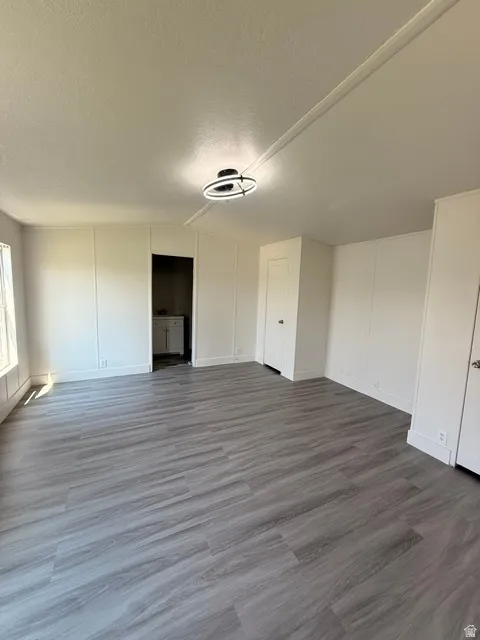 Spacious interior with plank-style flooring, contemporary ceiling light fixture, panel accent walls, and white trim