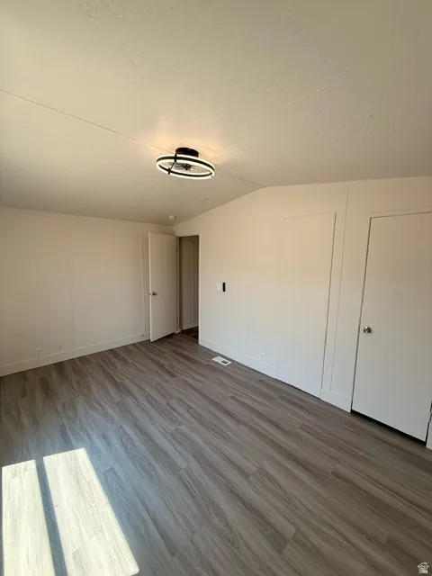 Wood-finish flooring throughout, bright white walls, and a contemporary ceiling light fixture