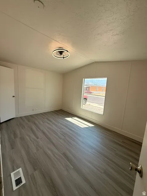 Laminate wood-finish flooring, a contemporary ceiling fan, and white painted walls